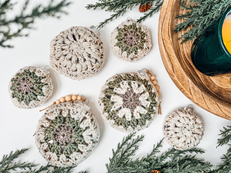 Handmade crochet christmas ornaments on a table next to a candle.