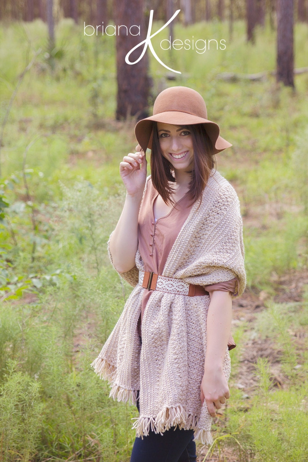 A woman wearing a cream crochet shawl wrap and hat, in a field of greenery.