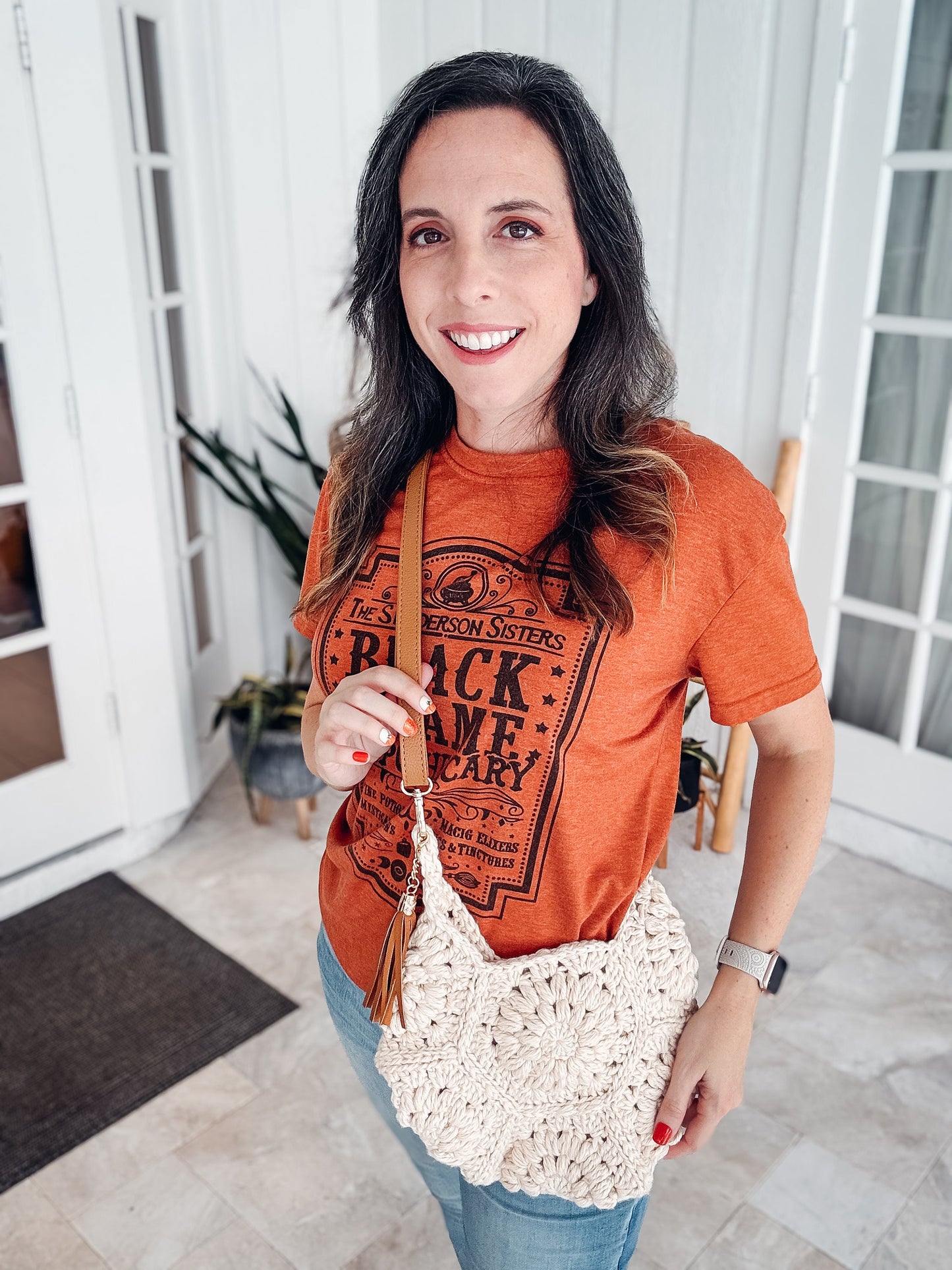 A woman wearing vintage clothes and holding a crocheted purse.