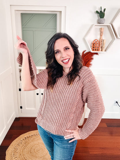 Dusty pink ribbed crochet sweater worn by a smiling woman holding up one sleeve to show its length
