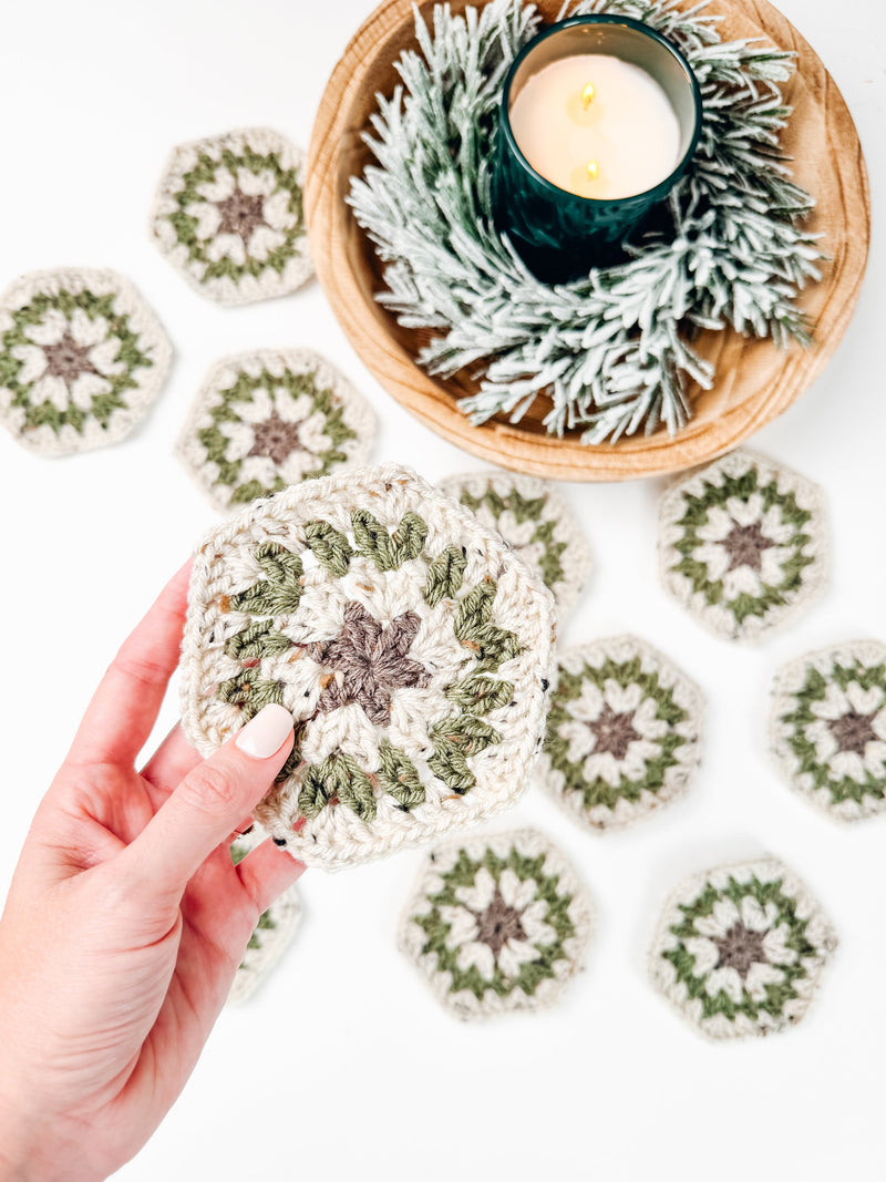 A person holding a crocheted coaster next to a candle, showcasing a unique handmade gift.