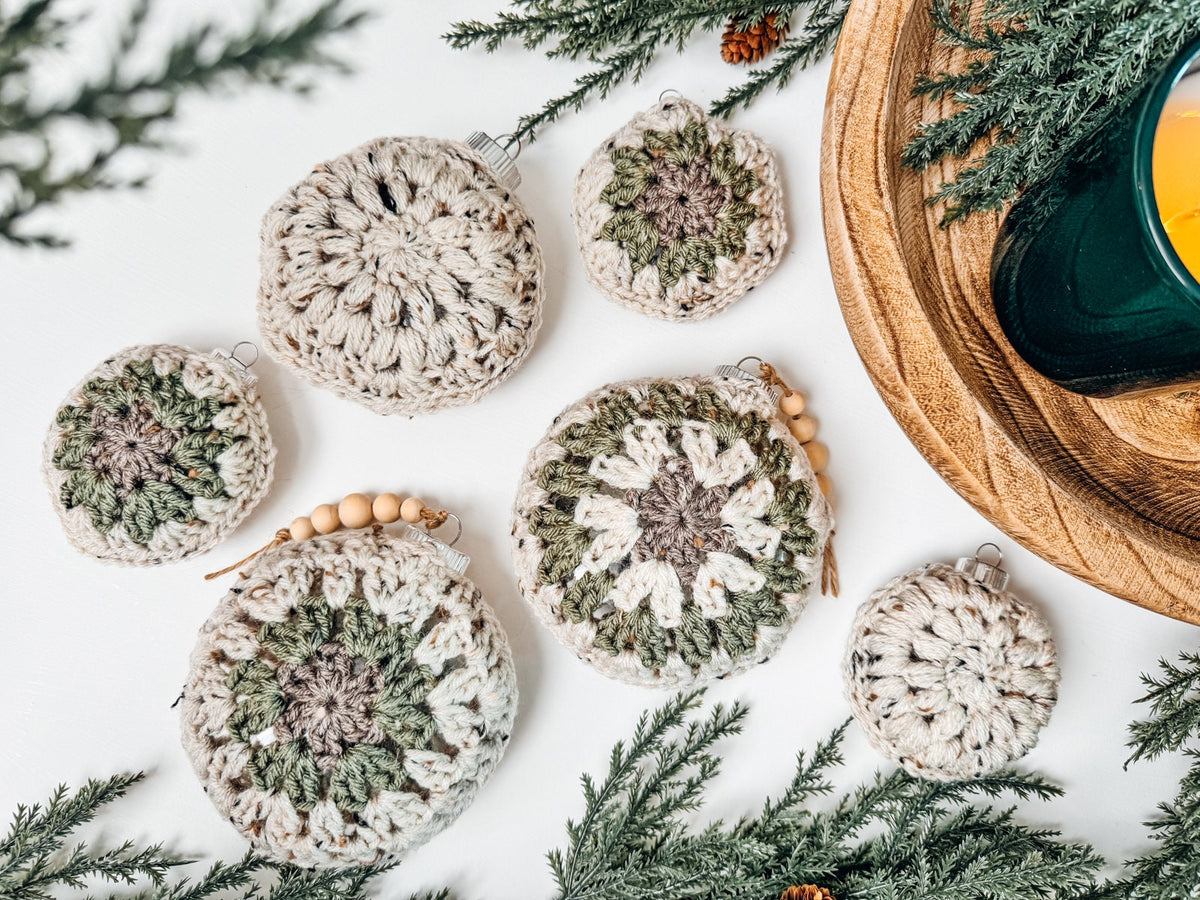 Handmade crochet christmas ornaments on a table next to a candle.