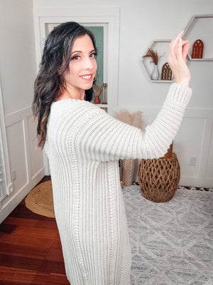 Cream crochet cardigan shown from the side with ribbed sleeve and textured panel as the woman raises one arm