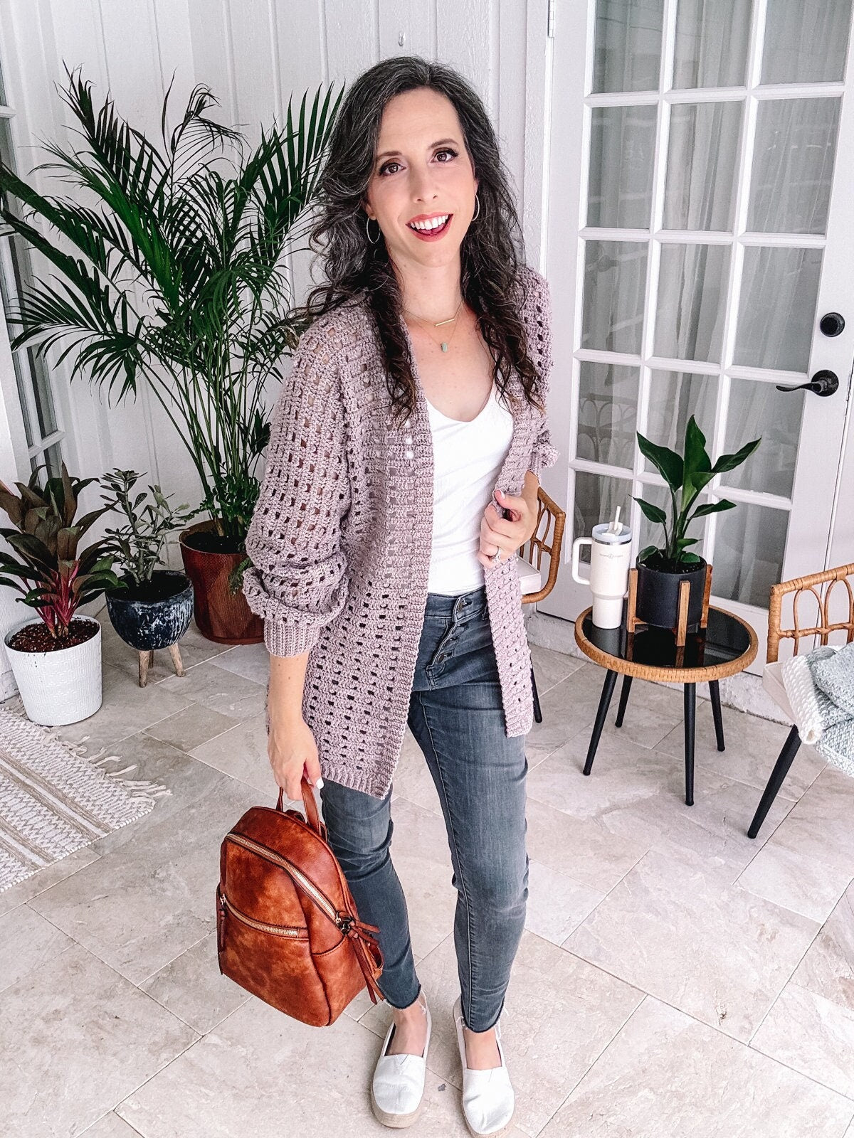 Woman posing with a smile in a casual outfit featuring unique jewellery at home.