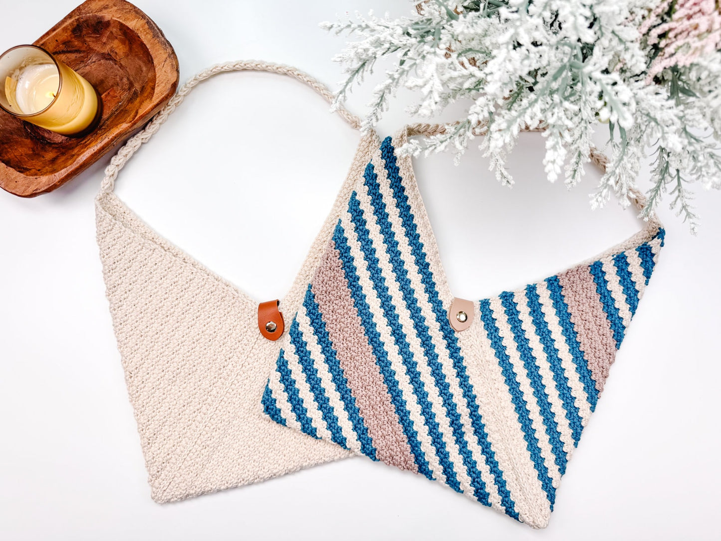 Two crocheet bags on a white surface; one is plain cream-colored, the other has blue, grey, and cream stripes. Each features a button closure.
