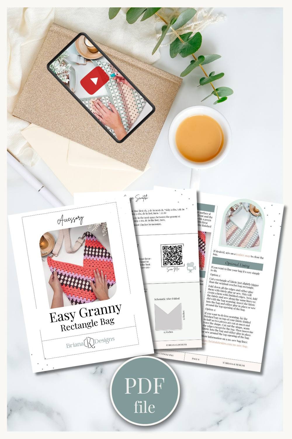 A workspace showcasing a PDF file on crochet patterns, a phone playing a crochet video, a cup of coffee, an envelope, and some greenery—perfect for crafting handmade gifts.