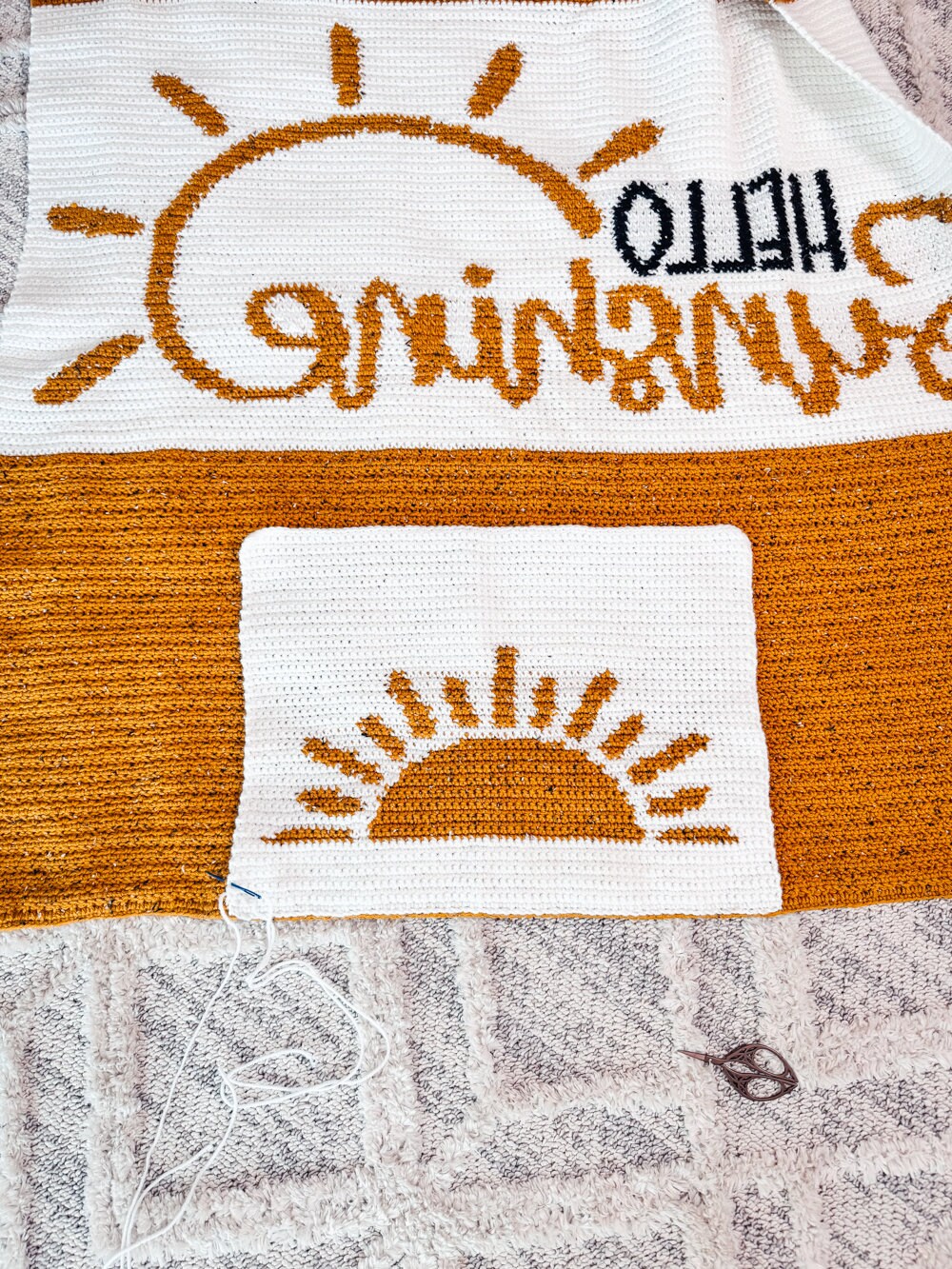 A knitted blanket with sun and words, perfect as a handmade gift.
