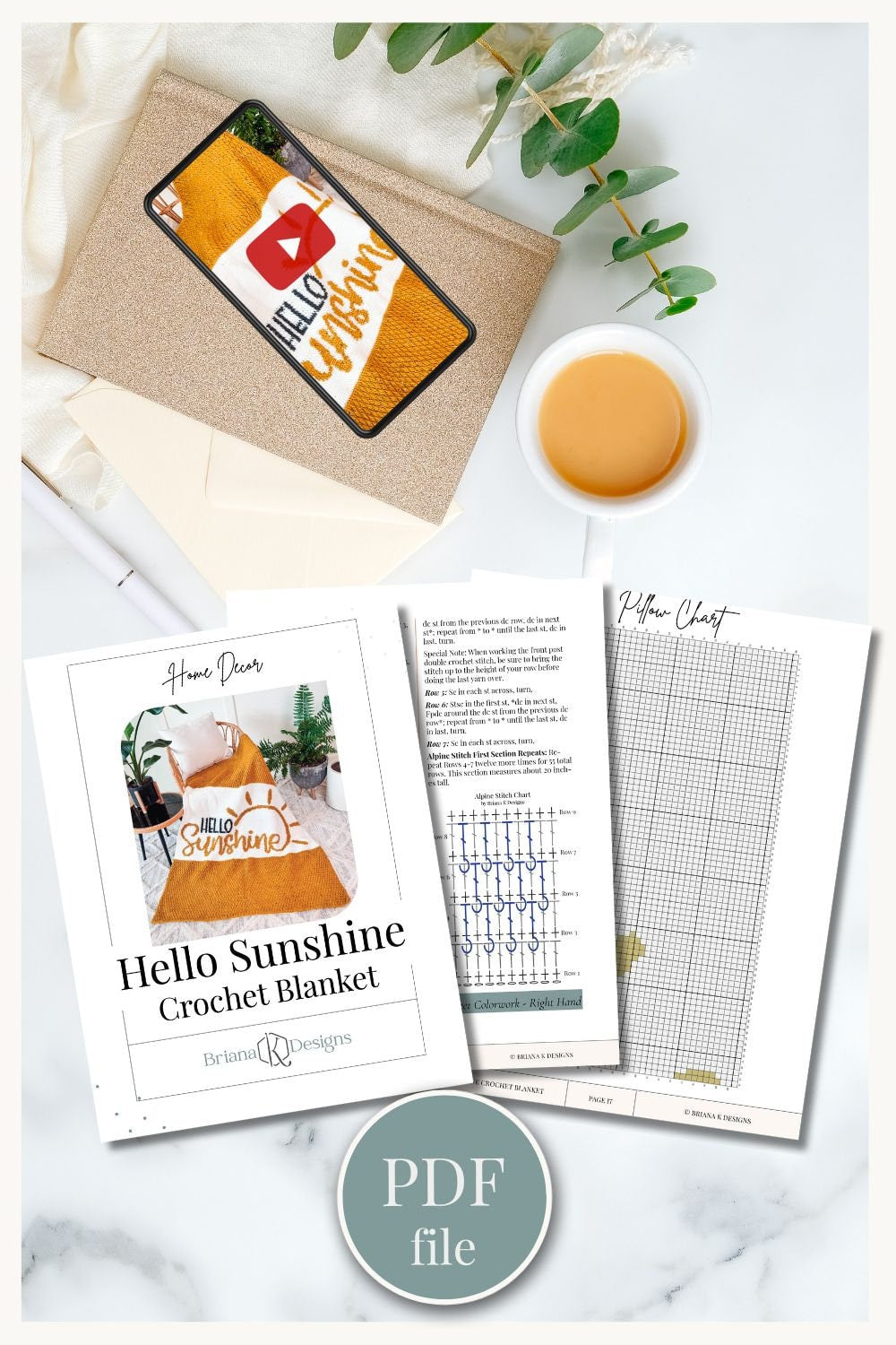 An instructional PDF file for making a "Hello Sunshine" crochet blanket is displayed beside a cup of tea, a brown envelope, and leaves. The PDF includes diagrams and a photo of the finished product, perfect as a handmade gift.