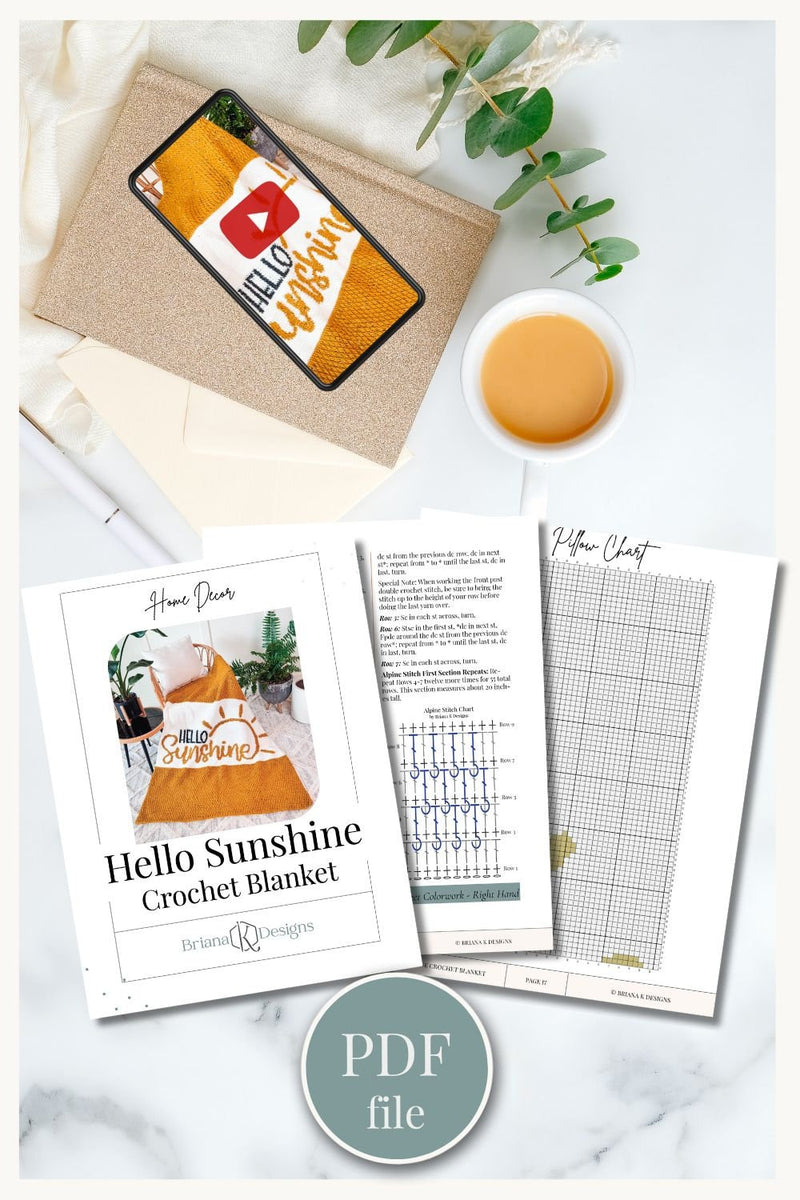 Crochet pattern PDF pages with stitch charts beside a phone showing the video tutorial and a cup of tea