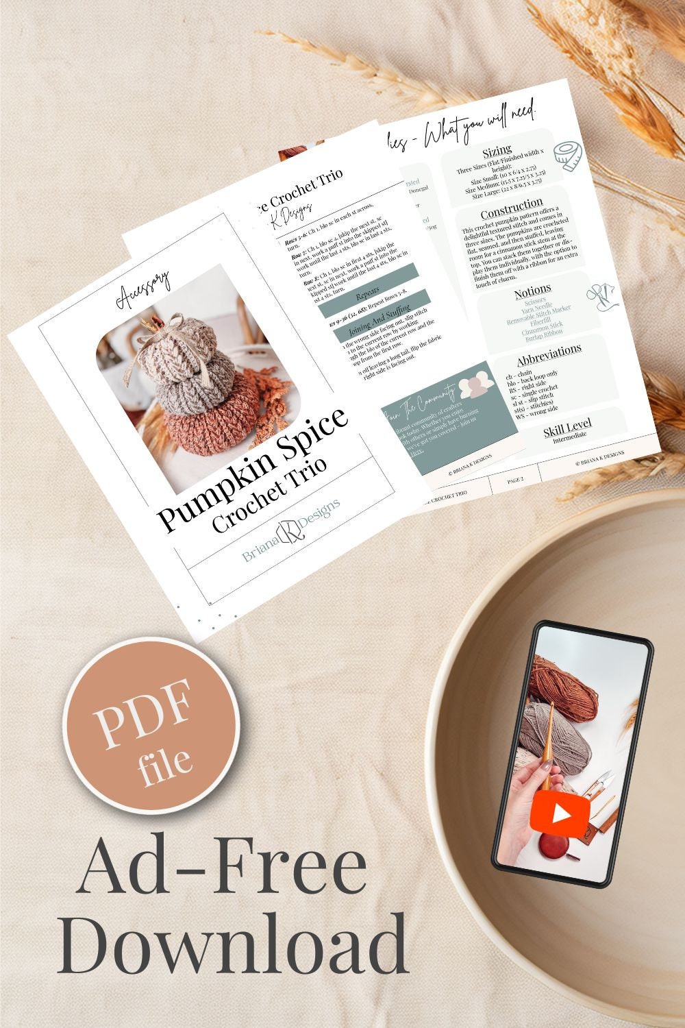 A crochet pattern for a Pumpkin Spice Crochet Trio is displayed on a table alongside a bowl and a phone showing a crochet video. The text highlights an ad-free, PDF file download, making it perfect for crafting handmade gifts.