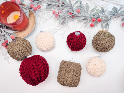 A decorative arrangement of handmade rocheted ornaments in red, brown, and cream alongside a red candle and frosted leaves with berries on a white surface. Perfect as a thoughtful gift.