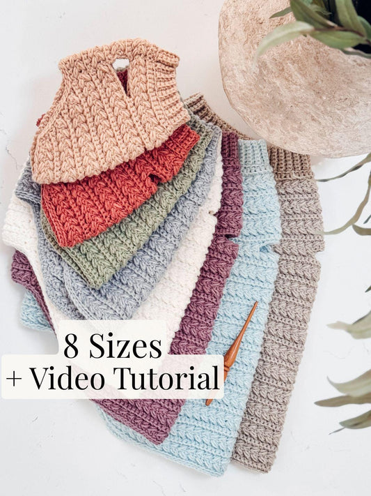 Stack of eight crocheted sweaters in various colors displayed next to a crochet hook, perfect as a handmade gift. Text reads "8 Sizes + Video Tutorial.