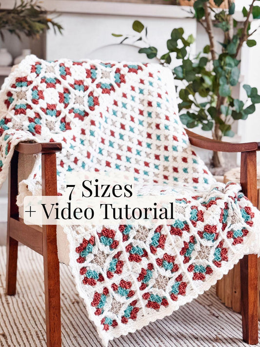 A crocheted blanket with a colorful geometric pattern draped over a wooden chair, with text overlay reading "7 Sizes + Video Tutorial." Plants, a rug, and touches of vintage clothes create the perfect backdrop for this handmade gift.