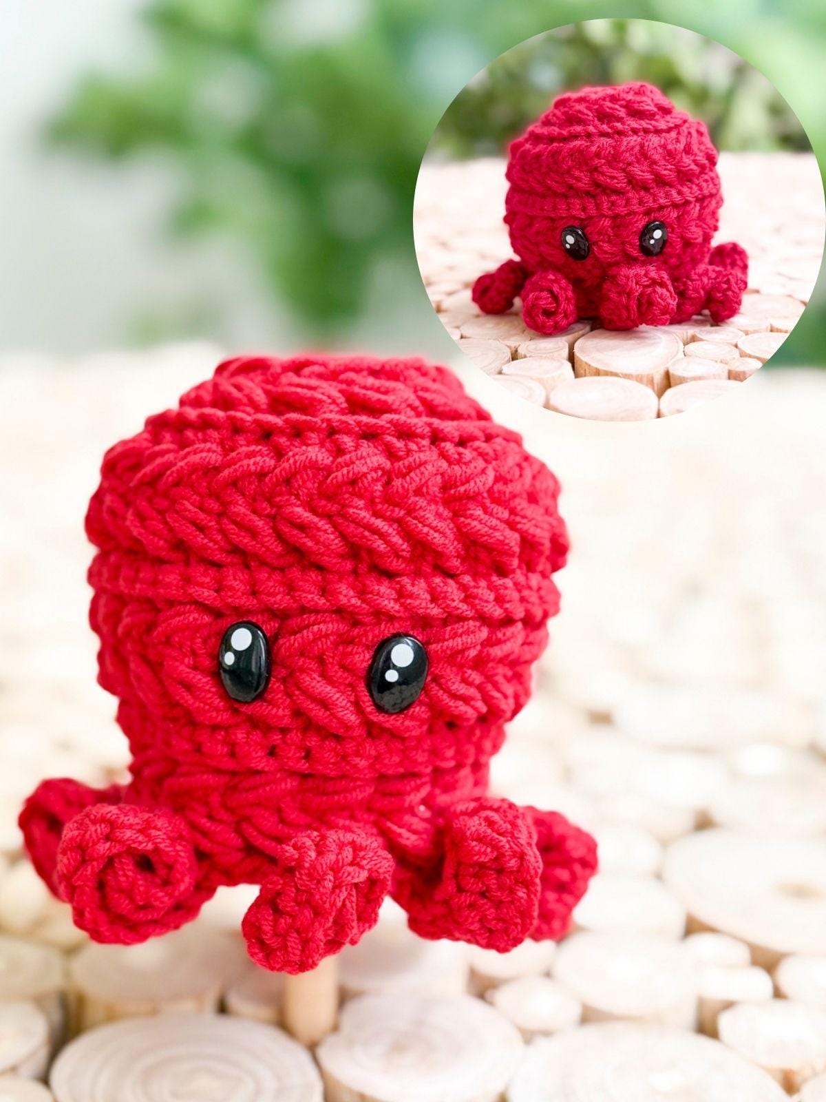 A small, red, crocheted octopus with large black eyes is displayed on a light wooden surface. An inset shows a close-up of the same crocheted octopus—a perfect handmade gift for fans of unique jewellery and charming crafts.