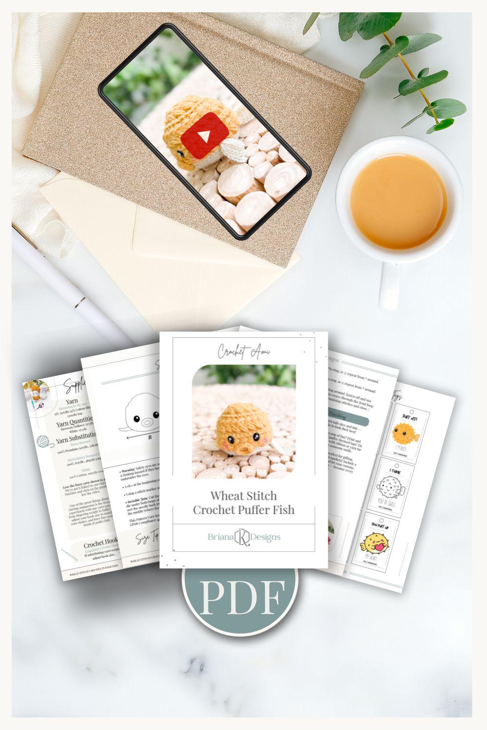A crochet puffer fish pattern PDF and printed instructions are displayed on a table with a cup of tea, an envelope, and a phone showing a crochet video tutorial—perfect for crafting a handmade gift.