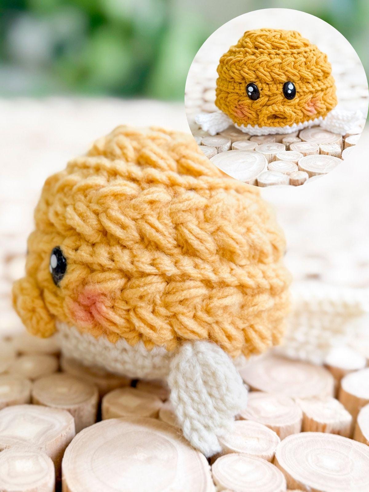 A small, yellow crocheted fish with black eyes and cream-colored fins sits on a wooden surface; an inset shows a similar yellow crocheted ball with eyes—perfect as a handmade gift for someone who loves charming creations.