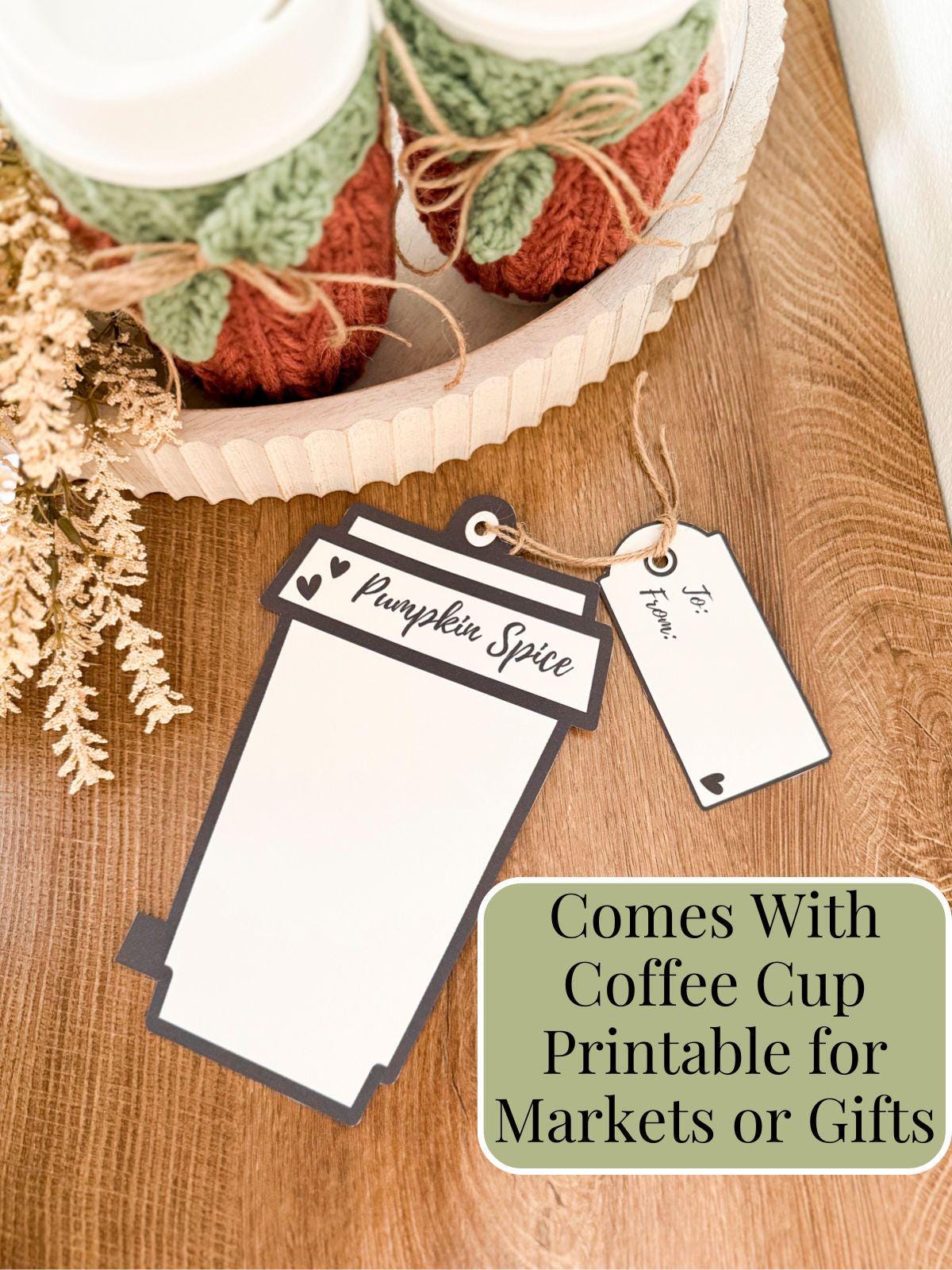 Two takeaway coffee cups with crochet cozies sit in a tray next to a pumpkin spice coffee cup-shaped gift tag and a blank gift tag, creating the perfect handmade gift. Includes a note about printable gift tags.