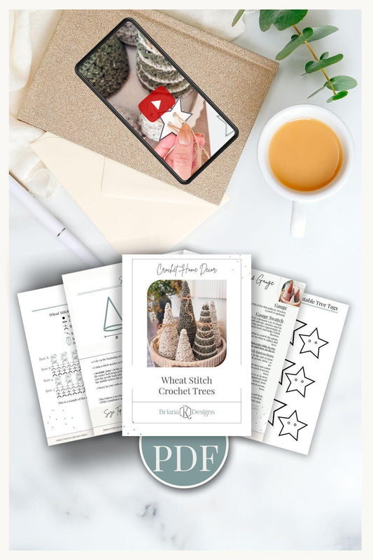 A flat lay of a crochet pattern PDF titled "Wheat Stitch Crochet Trees," printed pages, a cup of tea, an envelope, and a tablet displaying a crochet video—perfect inspiration for crafting a handmade gift.