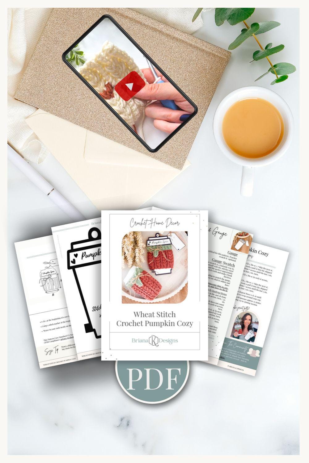 A flat lay of a crochet pattern PDF, printed pages, a phone showing a crochet video, an envelope, unique jewellery pieces, and a cup of tea on a light surface—perfect inspiration for your next handmade gift.