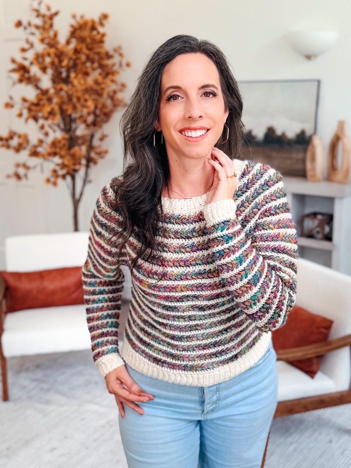Crocheted Wheat Stitch Sweater shown in vibrant yarn colors on a smiling woman; overlay text notes the pattern includes 9 sizes and guided sleeve decreases, ideal for a thoughtful handmade gift.