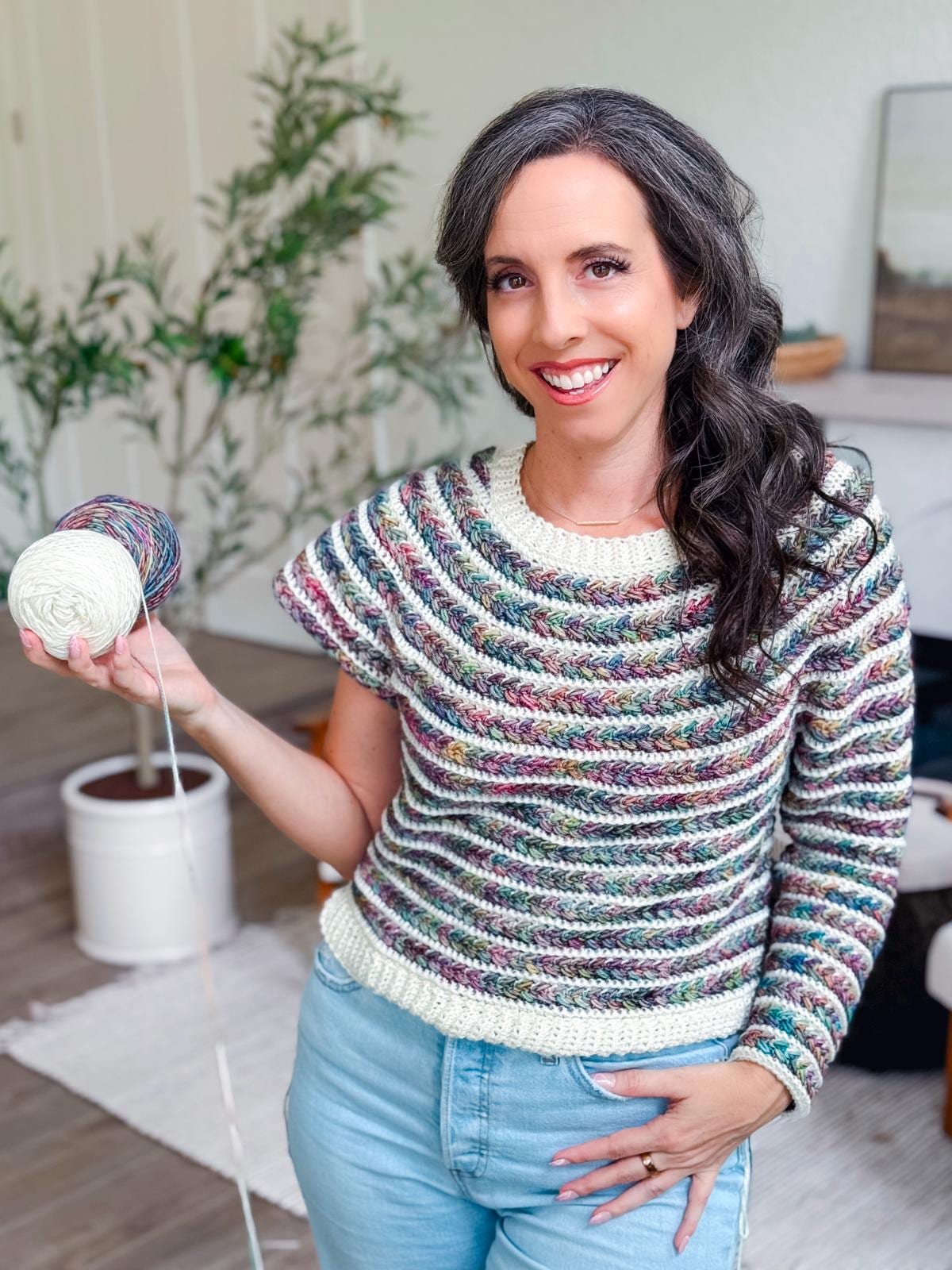 Smiling woman showcases a colorful crochet Wheat Stitch Sweater; text overlay highlights 9 size options and guided sleeve decreases included in the pattern — a stylish, customizable gift to crochet.