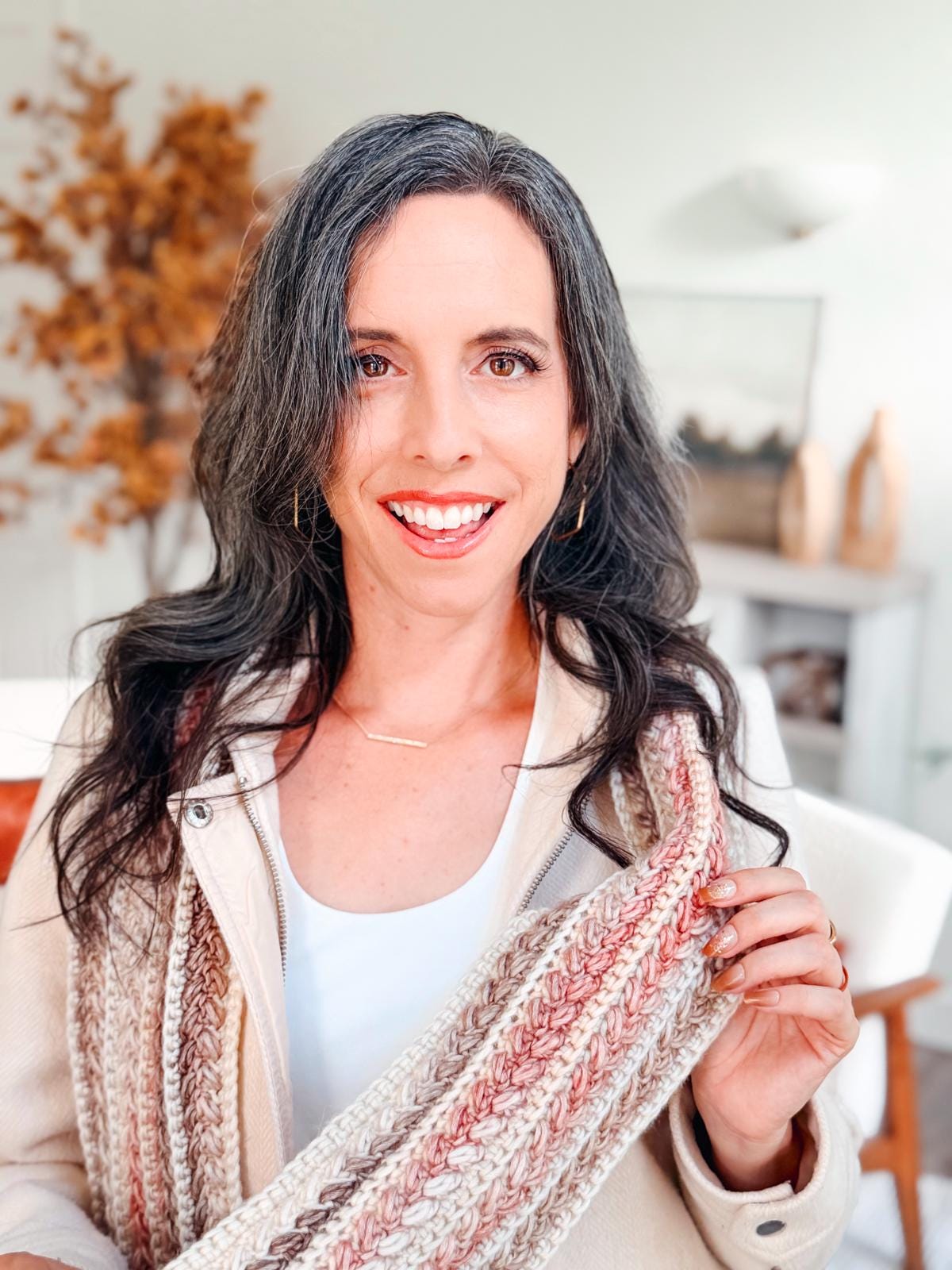 Crocheted items with vibrant multicolored yarn, wooden crochet hooks, printed instruction sheets, and handmade tags are artfully arranged on a surface crafted from stacked wooden pieces.
