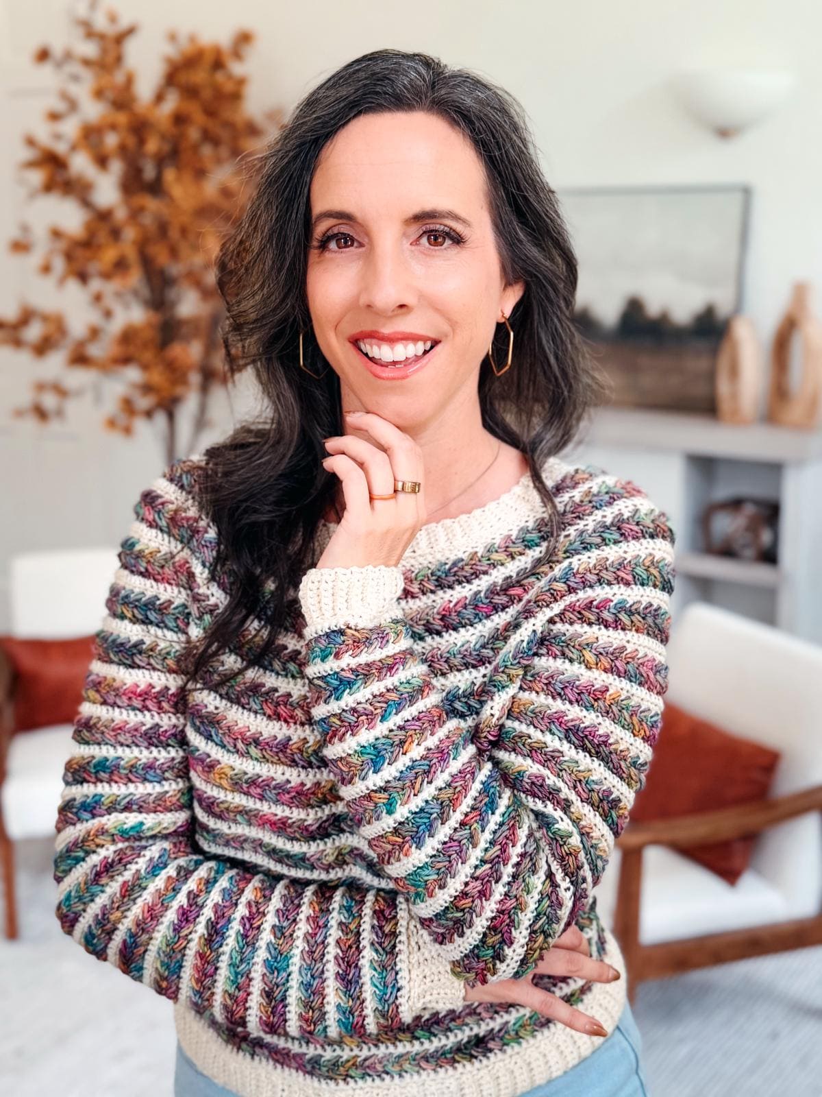 A woman models a textured, multicolor crochet sweater with ribbed details; text overlay mentions 9 available sizes and guided sleeve shaping, showcasing the Wheat Stitch Sweater pattern as a cozy make.