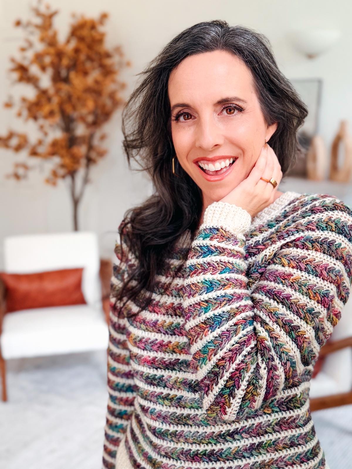 Smiling model wearing a modern crochet Wheat Stitch Sweater in multiple colors; overlay text highlights 9 inclusive sizes and guided sleeve decreases, perfect for crocheters making handmade gifts.