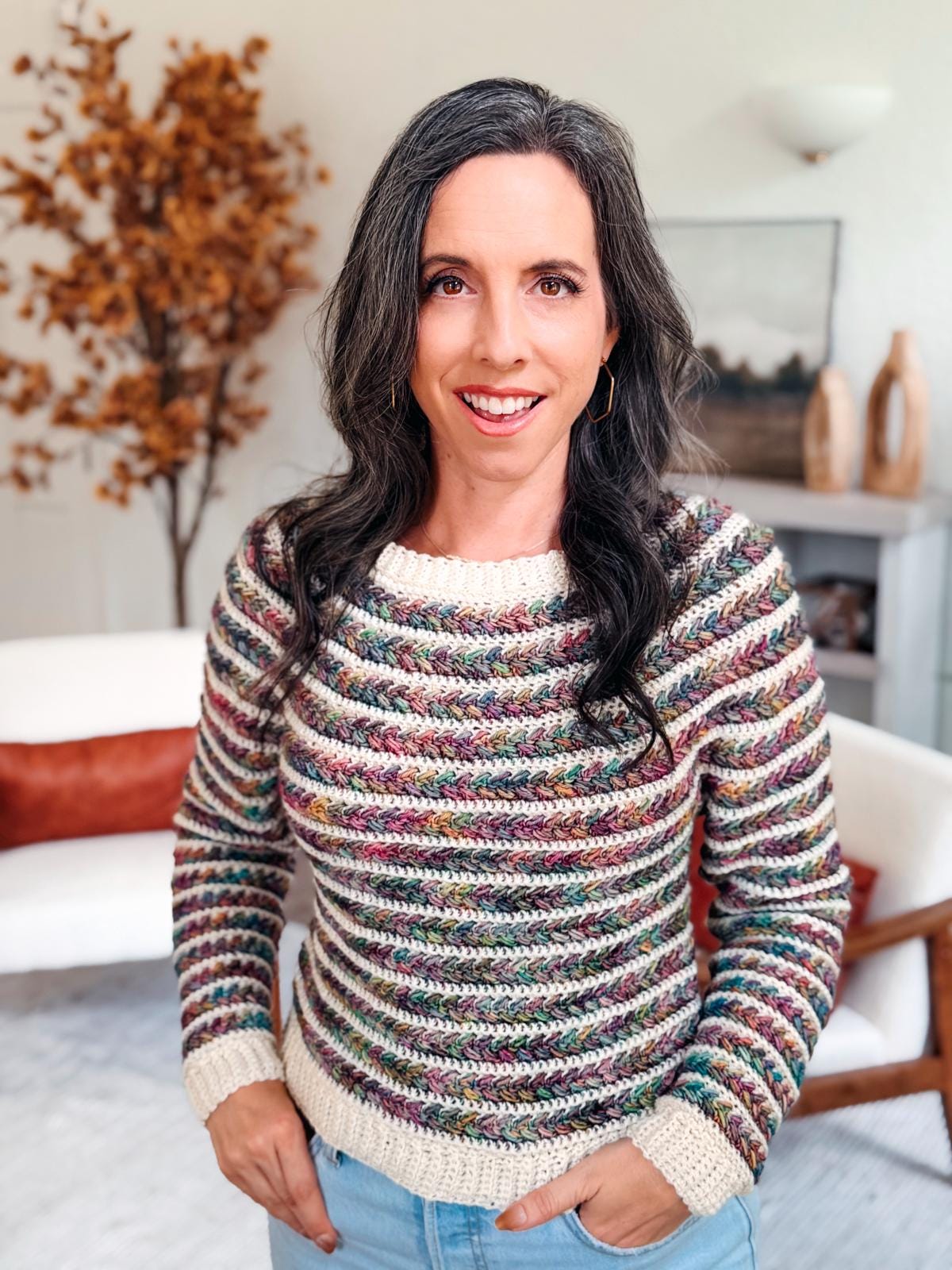 Woman wearing a handmade Wheat Stitch Crochet Sweater in vibrant colors smiles at the camera; overlay text promotes 9 sizes and step-by-step sleeve shaping, ideal for creating a cozy handmade gift.