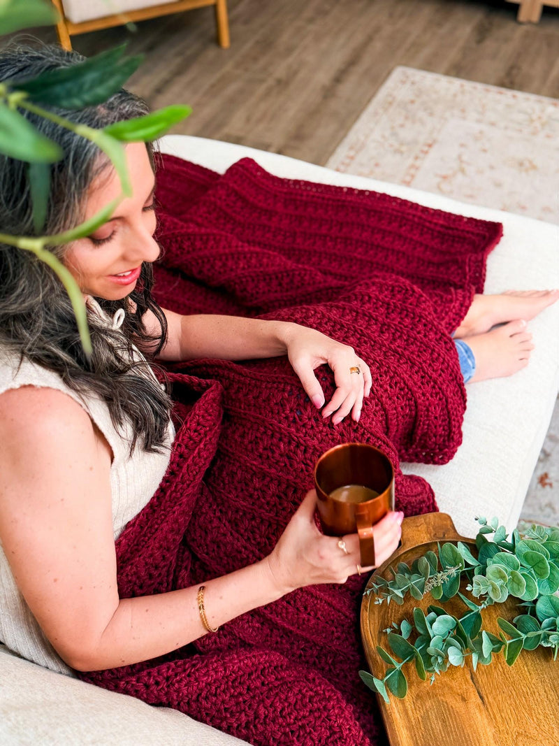 Deep red Petal Loop Stitch crochet blanket, a cozy textured throw, across a lap