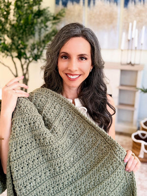 Sage green Petal Loop Stitch crochet blanket wrapped over the shoulders