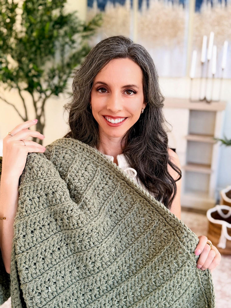 Sage green Petal Loop Stitch crochet blanket wrapped over the shoulders