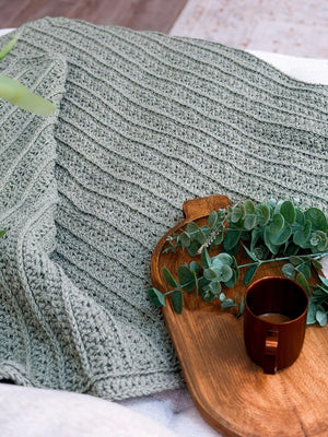 Close up of the Petal Loop Stitch texture on a sage green crochet blanket