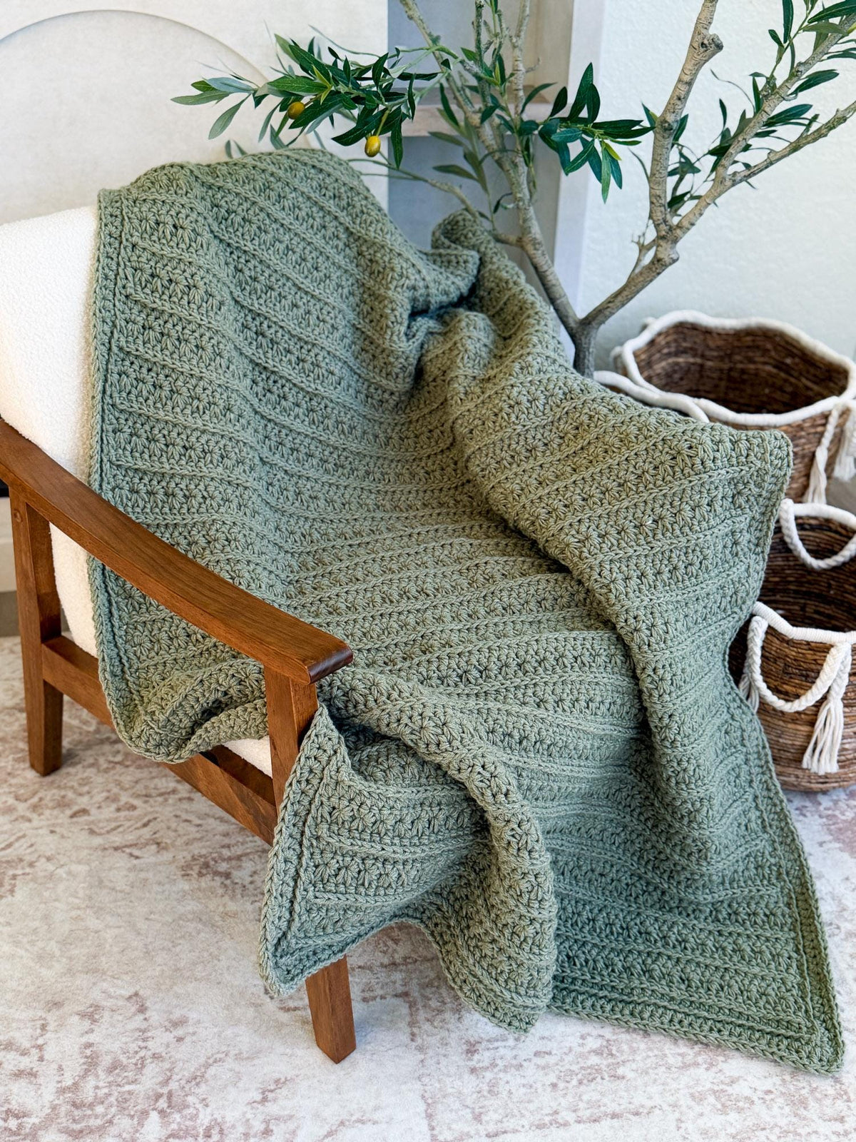 Sage green textured crochet blanket draped over a wooden chair
