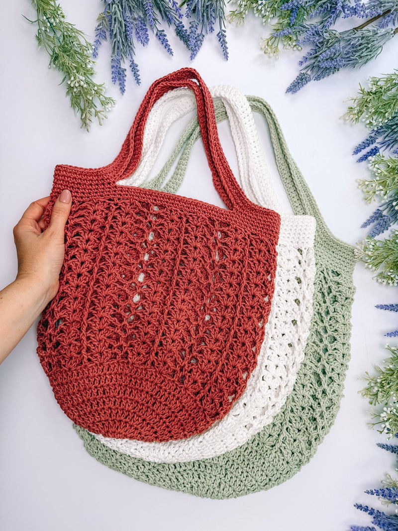 Terracotta Willow Mesh crochet market bag held up with cream and sage bags behind