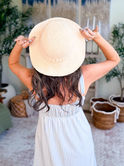 Cream crochet sun hat seen from behind on a woman holding the brim with both hands