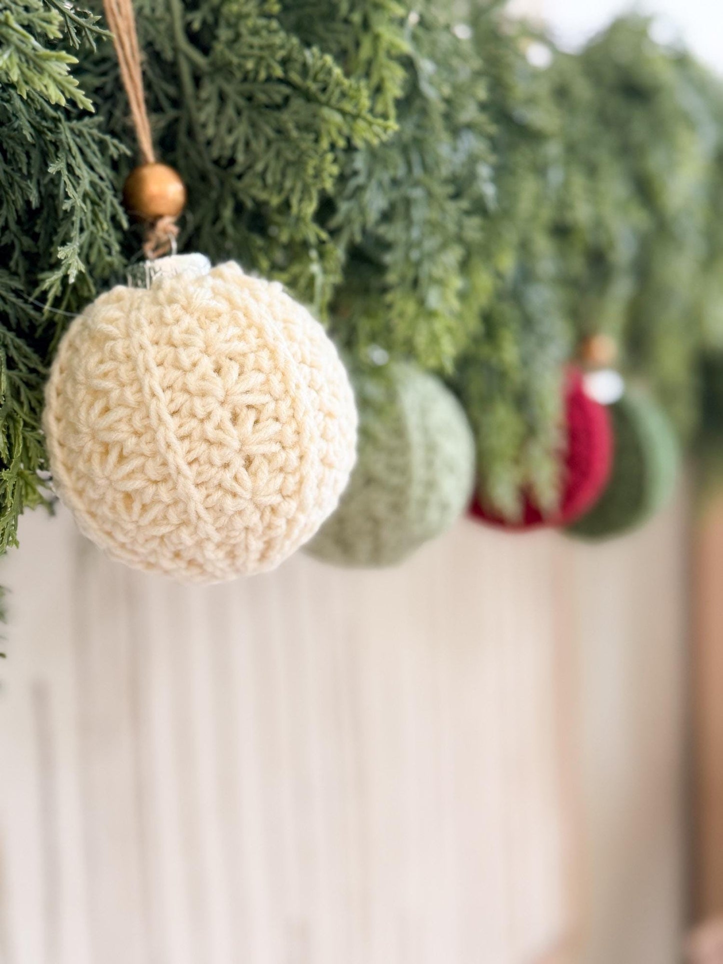 Crocheted beige ornament hanging on a Christmas tree with blurred background