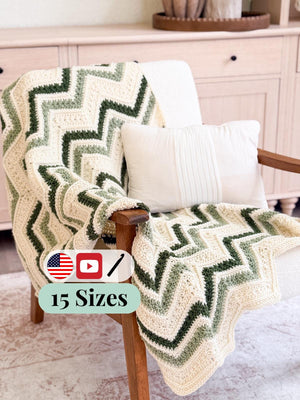 Cream and green chevron crochet blanket draped over a wooden armchair with a white pillow