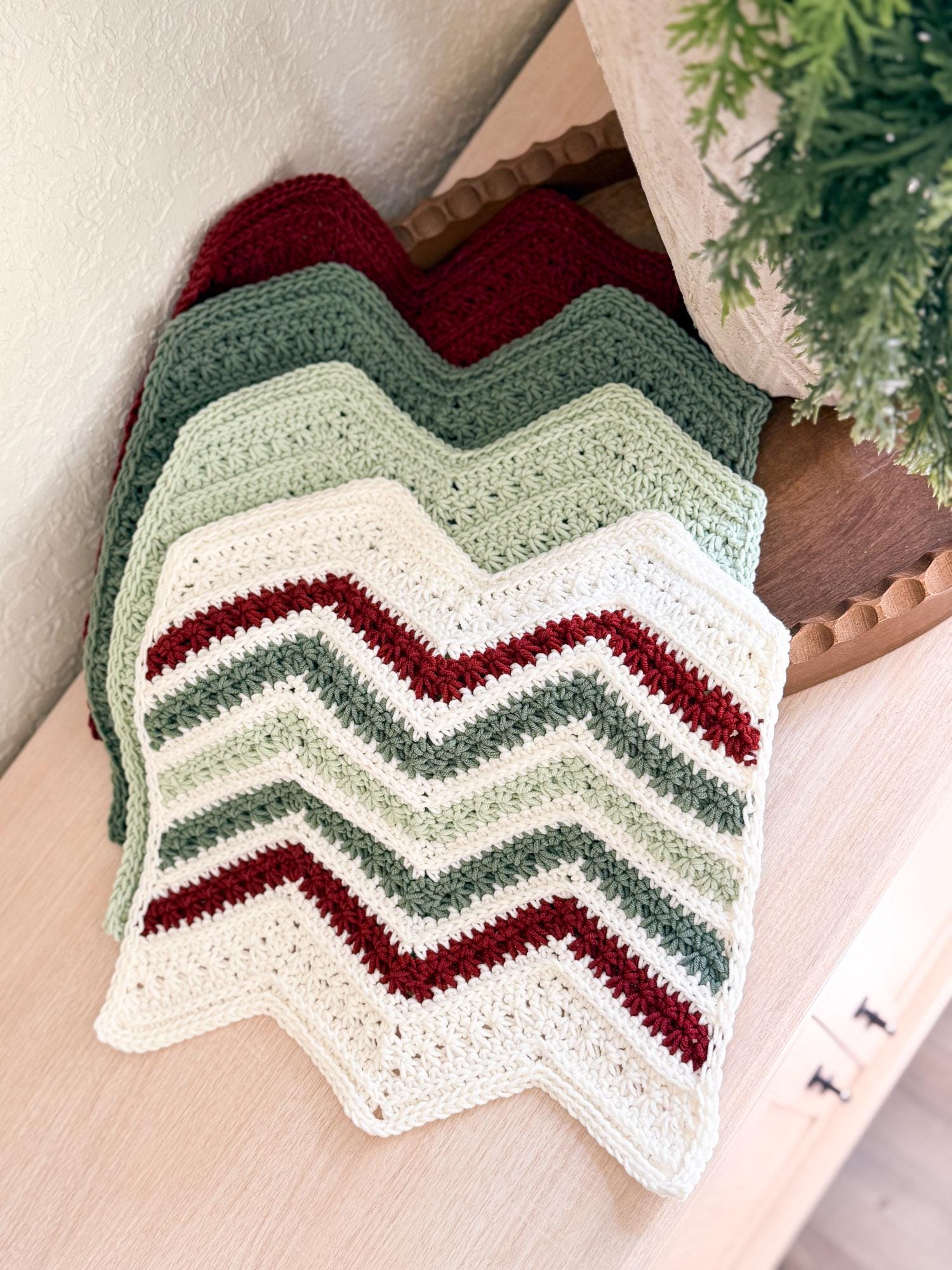 Crocheted dishrag with chevron pattern in red, green, and white on a wooden surface.
