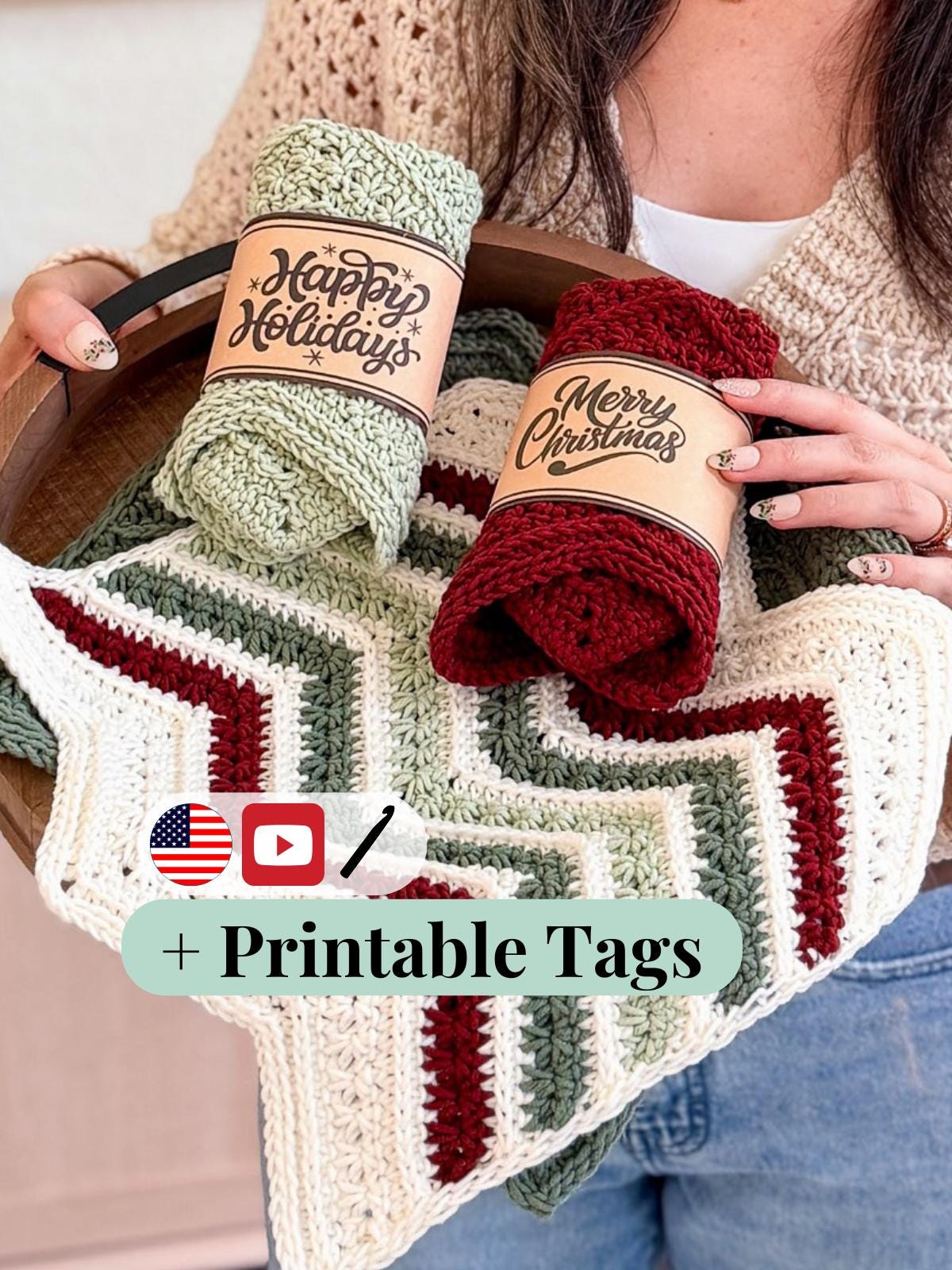 Person holding a crocheted blanket with yarn rolls labeled 'Happy Holidays' and 'Merry Christmas'.